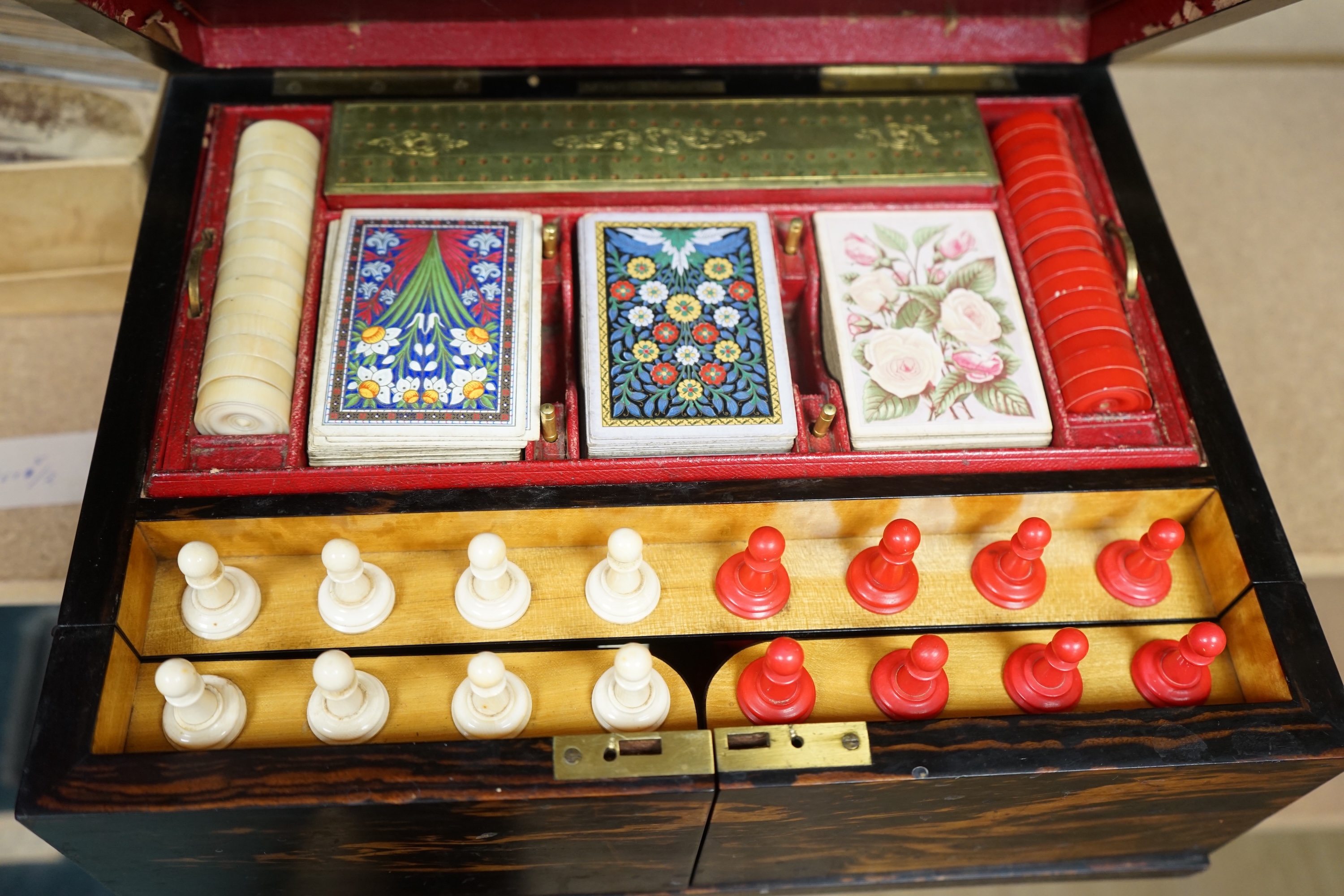 A Victorian coromandel games box with accessories, ivory chess pieces and counters, box 36cm wide x 19cm high. Condition - red interior leather worn and torn in places and box scratched, minor losses to chess pieces. CIT